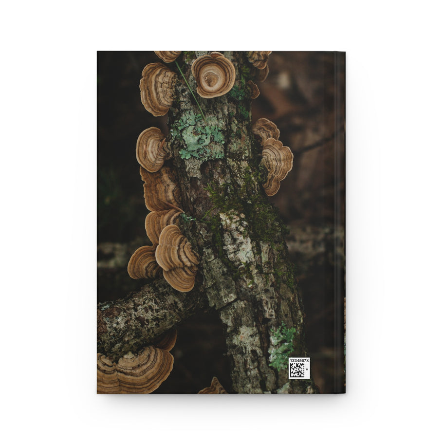 A hardcover notebook featuring a cover print of brown shelf mushrooms growing on a tree trunk with green moss, shown against a plain white background.