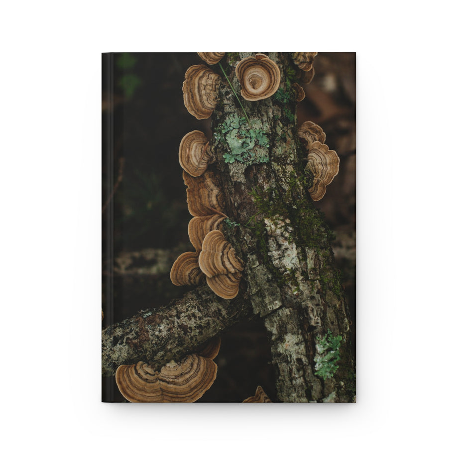A hardcover notebook featuring a cover print of brown shelf mushrooms growing on a mossy tree trunk, shown against a plain white background.