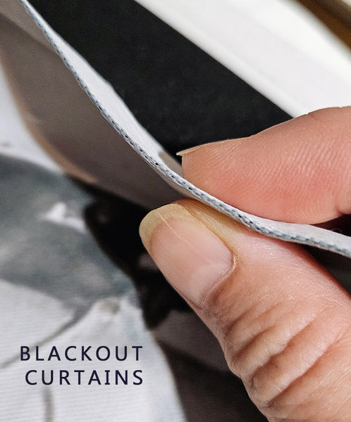 Close-up of a hand holding the edge of a black curtain panel to show its white backing, with the text 'BLACKOUT CURTAINS' in the lower left corner.