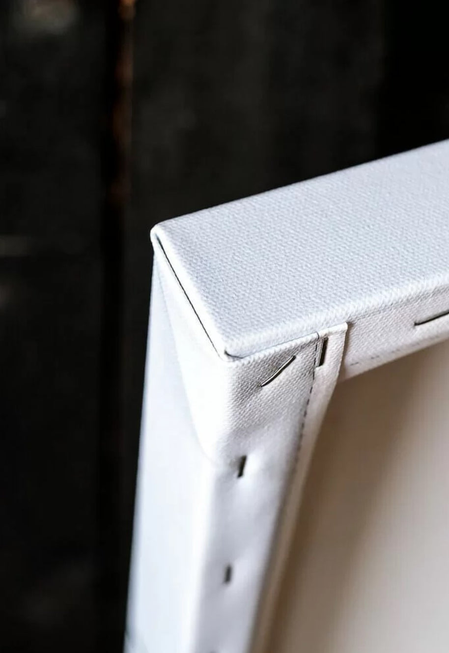 the back side of a wood stretcher canvas print with an open back - a corner detail where the cotton fabric is folded