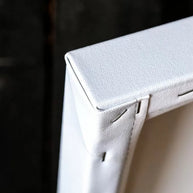 the back side of a wood stretcher canvas print with an open back - a corner detail where the cotton fabric is folded
