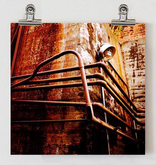 Rusty industrial metal pipe railing converging pipes with vintage wall lamp and light leaks on weathered brick wall