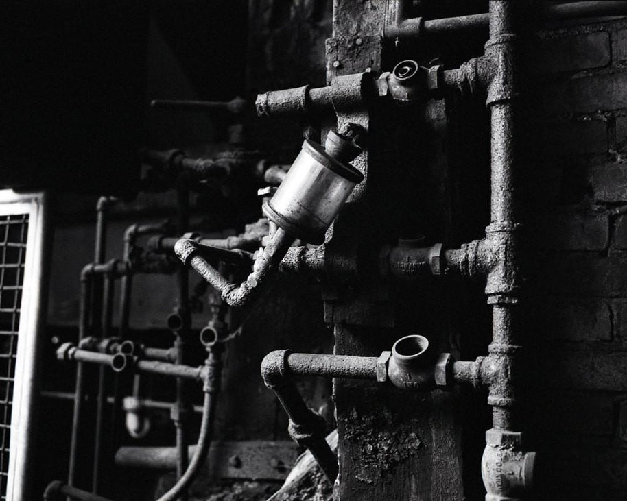 Rusty industrial pipe works with cylindrical metallic filter in white industrial photography style