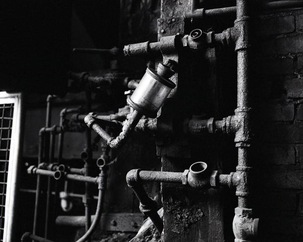 Rusty industrial pipe works with cylindrical metallic filter in white industrial photography style