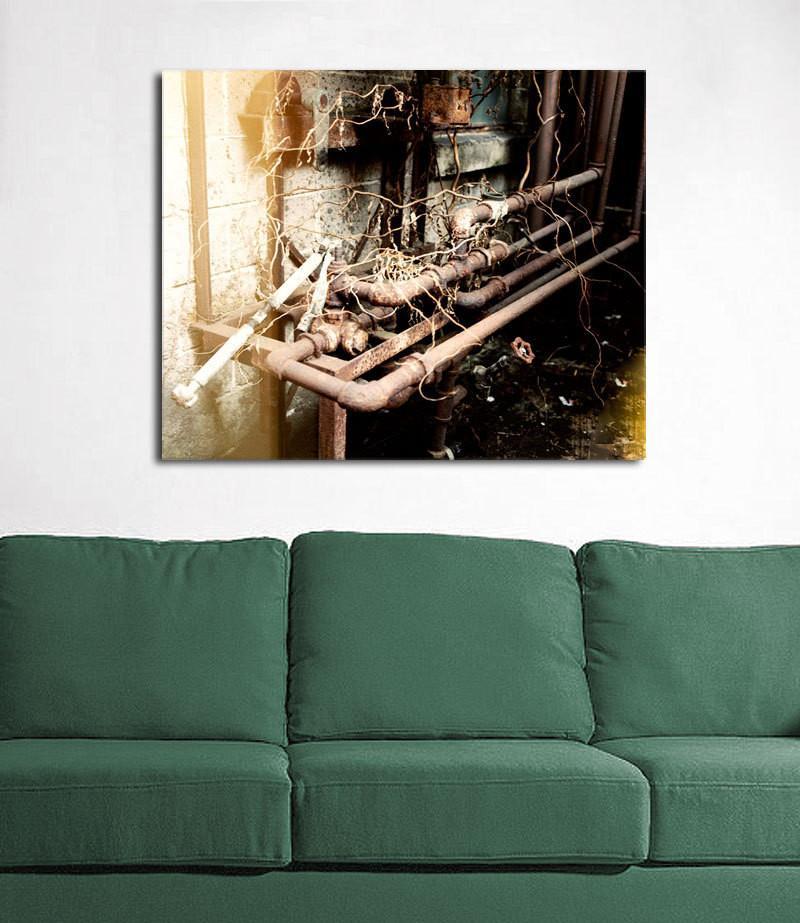 Rusty metalwork industrial photography print featuring rusty industrial pipe artwork above a green sofa