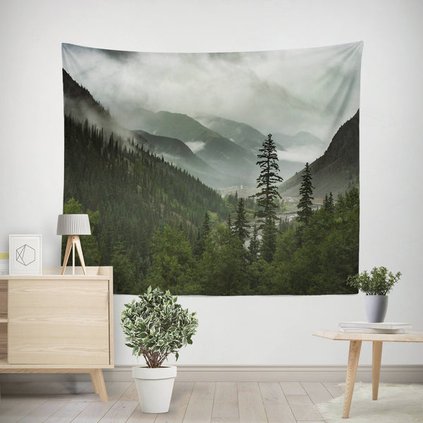 A Large Scenic Mountain Wall Tapestry featuring a foggy valley and pine forest surrounded by rolling peaks by Lost in Nature